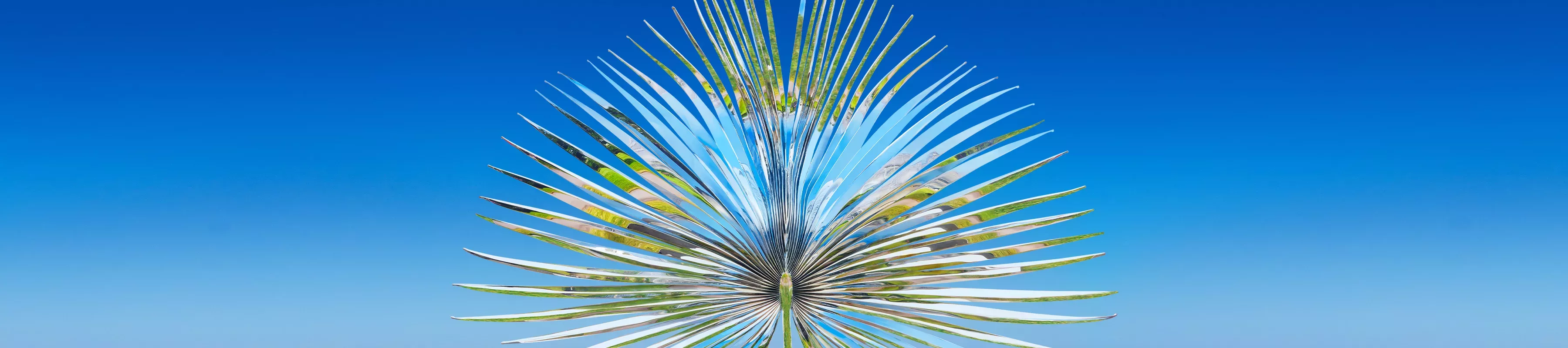 Marc Quinn: Light into Life © RBG Kew Reflective metal sculpture of palm frond against a blue sky