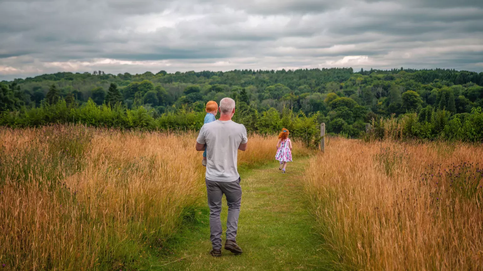Wakehurst Coronation Meadow, Visual Air © RBG Kew Father and two young daughters strolling through a meadow