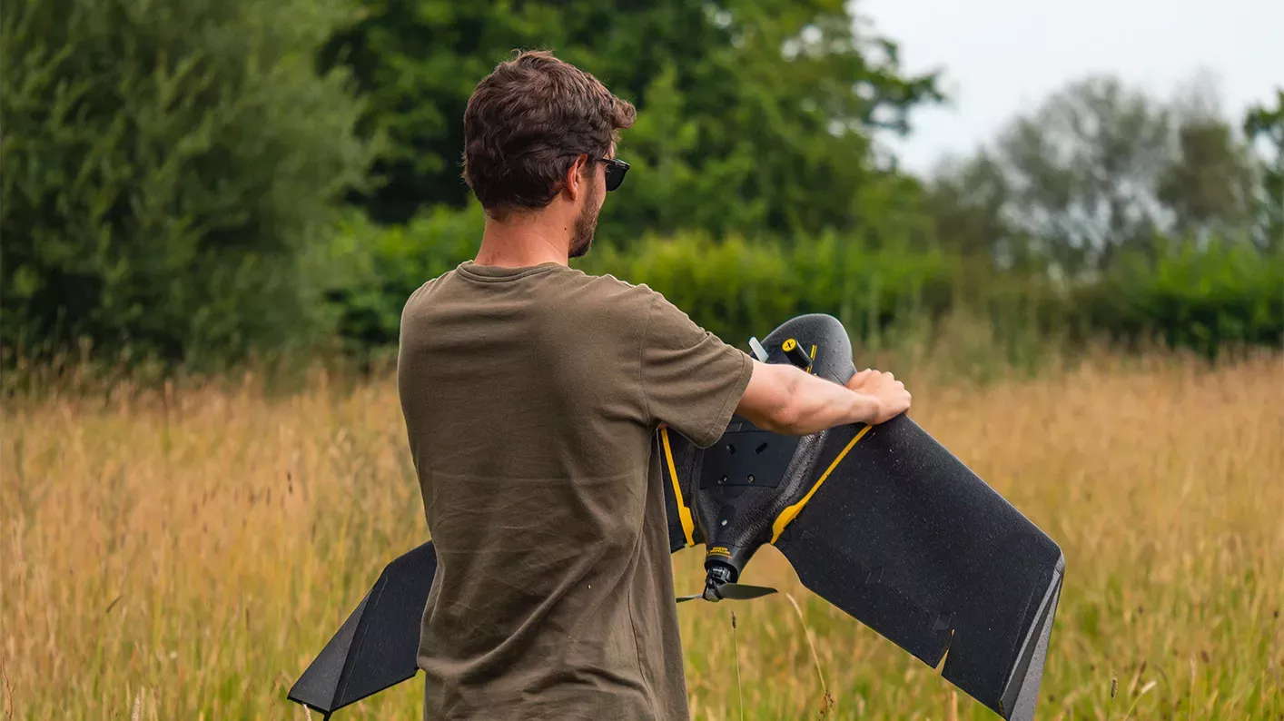 Spatial Analysis research, Visual Air © RBG Kew A scientist stands in a field holding a fixed wing drone